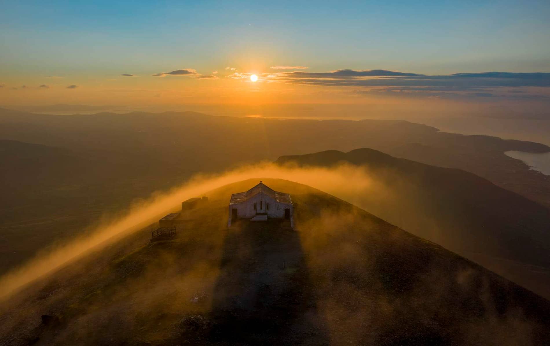 Puesta de sol anaranjada sobre Croagh Patrick con niebla sobre las montañas y el mar distante en el condado de Mayo.