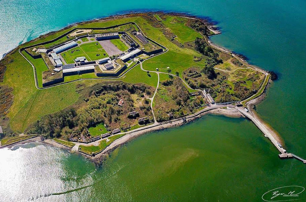 Vue aérienne de l'île Spike en forme d'étoile et de sa forteresse 19th-century entourée de champs verts et des eaux du port de Cork.