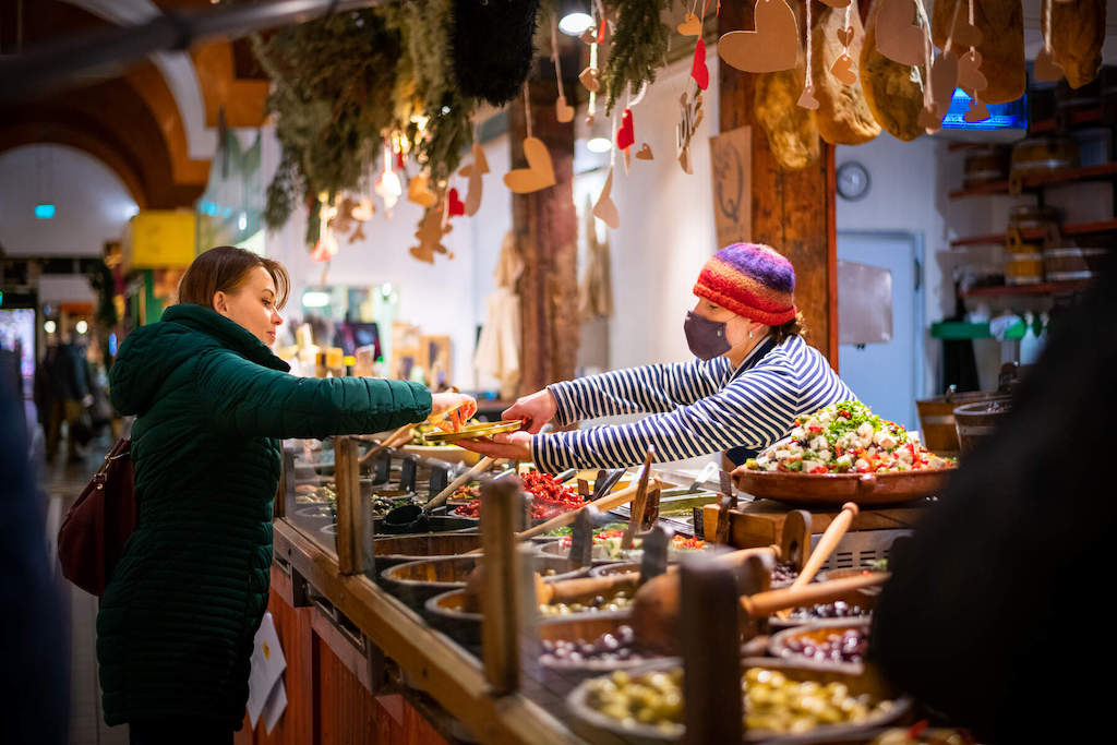 Un vendeur local donne de la nourriture à un client sur un stand de produits colorés sur le marché anglais de la ville de Cork.