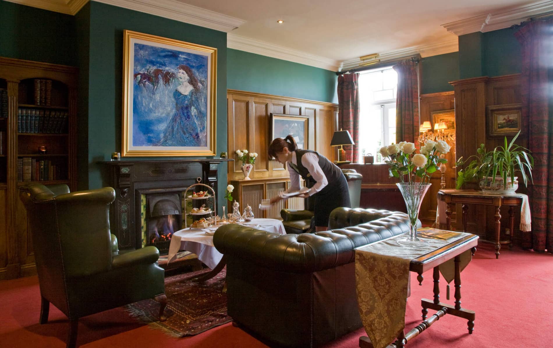 Serveuse plaçant Goûter à côté d'une cheminée dans le salon de Hayfield manoir un Hôtel de luxe à Cork.