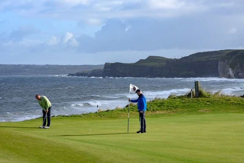 Royal Portrush Golf Club, dramatic links perched on the Antrim coast with waves crashing against rugged cliffs.
