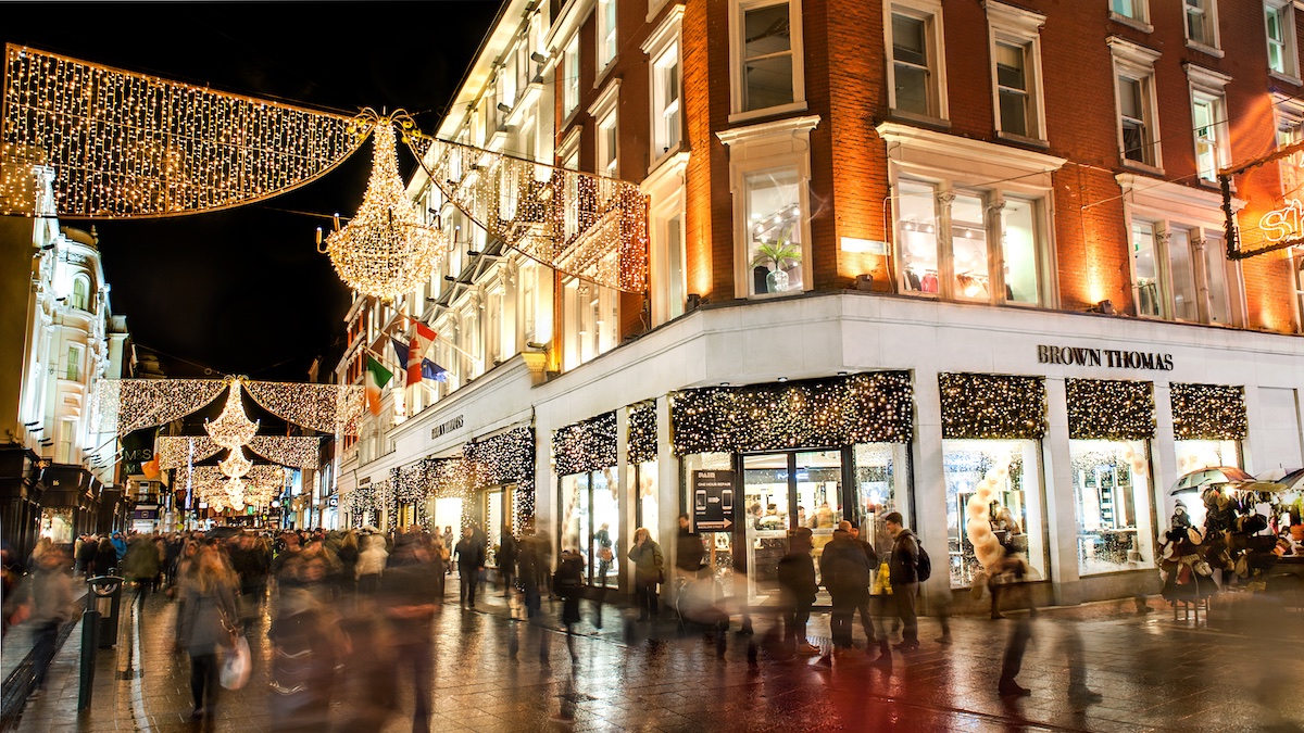 Menschenmengen, die unter Weihnachtslichtern auf der Grafton Street vor Brown Thomas in Dublin einkaufen.