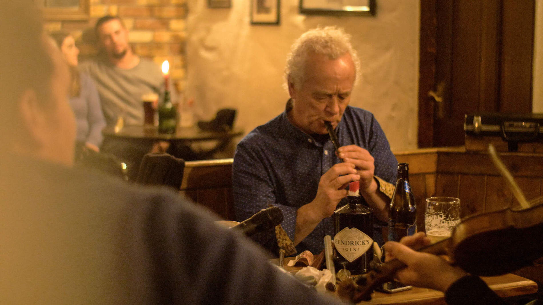 Traditionelle Musiker an einem Tisch in einem kerzenbeleuchteten Pub in Clare, darunter ein Tin Whistle-Spieler und andere auf Geige und Banjo.