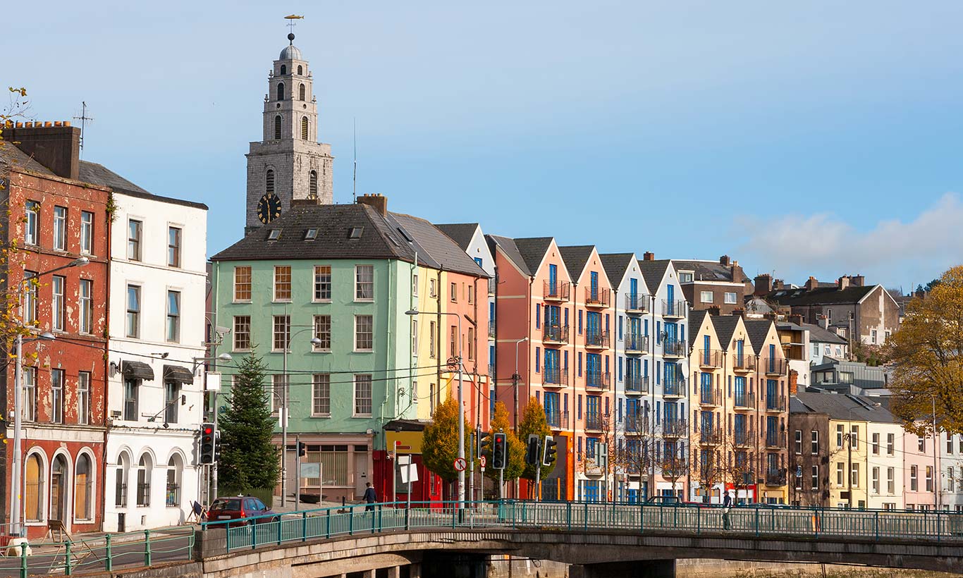 Kleurrijke huizen langs een straat in Cork met op de achtergrond de Shandon-toren.