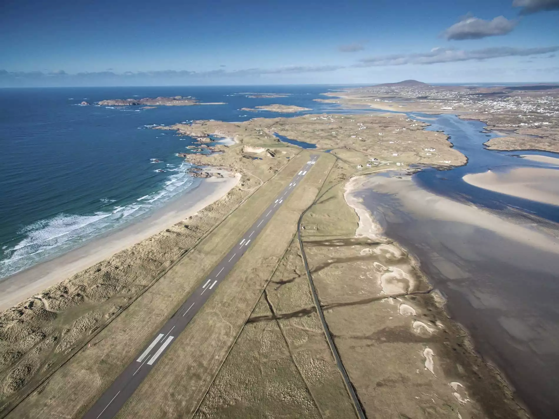Aerial view of Donegal Airport's coastal runway surrounded by beaches, dunes, and tidal inlets in County Donegal, Ireland.
