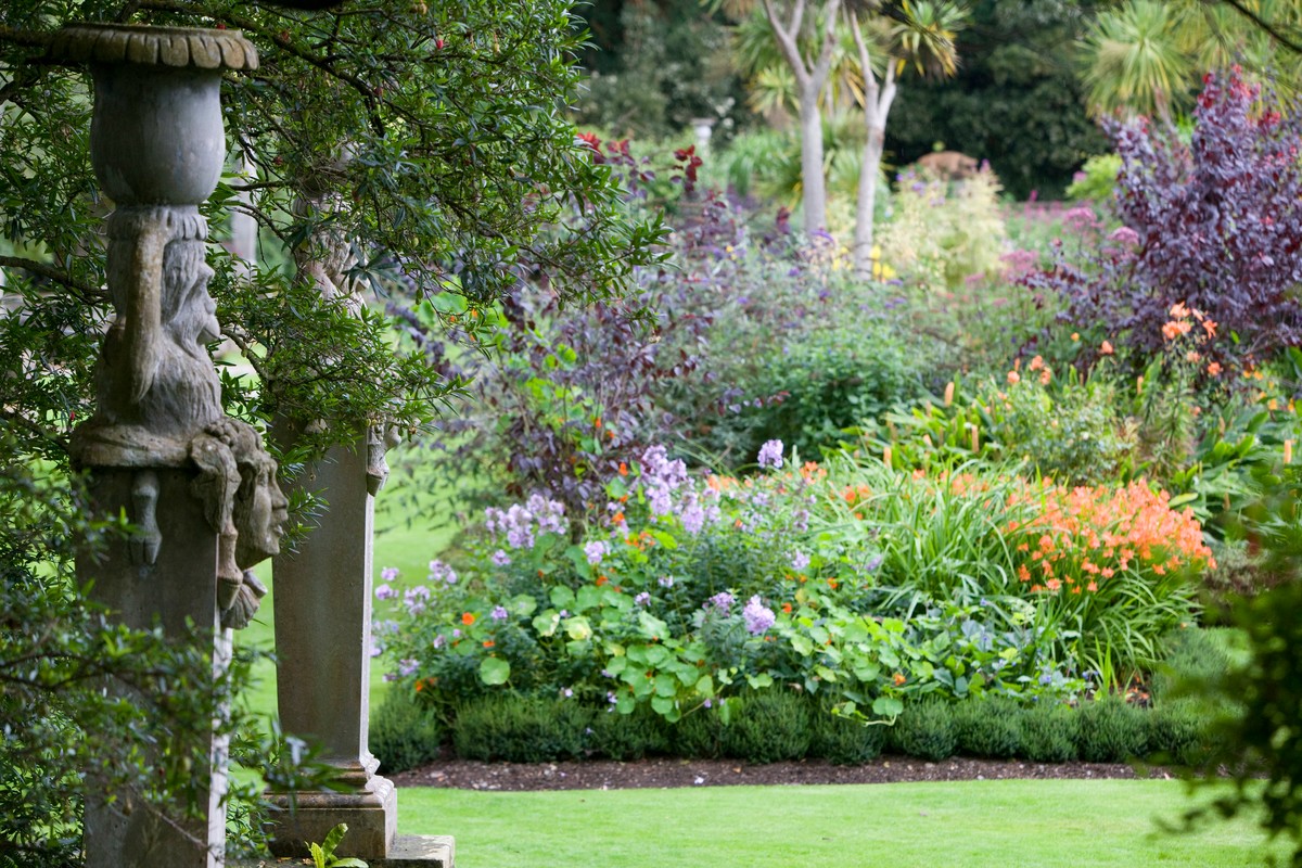 Een rijk versierde ommuurde tuin met levendige bloemen en netjes geschoren heggen voor de klassieke Mount Stewart, county Down.