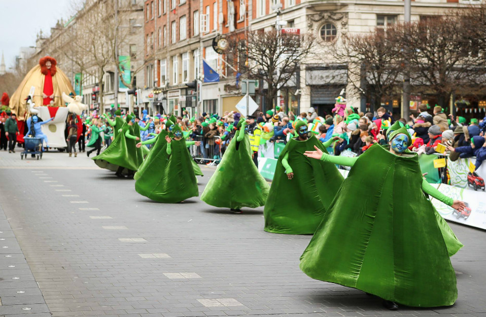 Deelnemers verkleed als klavertjesvier dansen langs O'Connell Street tijdens de St. Patrick's Day-parade in Dublin.