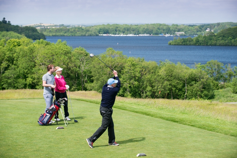Golfers play at Lough Erne Resort, Fermanagh, with tranquil blue waters and wooded shores as their backdrop.