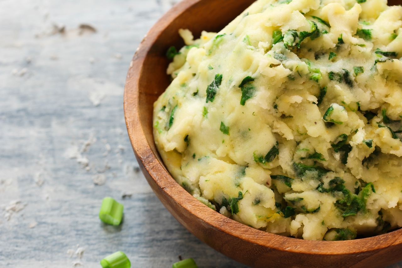 Close-up of colcannon mash with cabbage and spring onion in a wooden bowl.