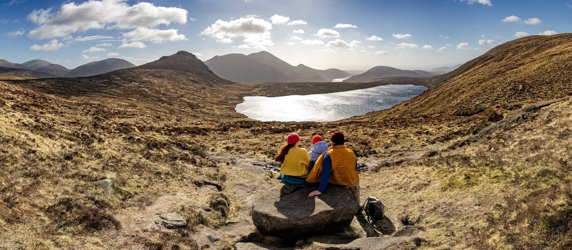 Group resting on a rock while overlooking a lake and mountain views in the Mourne Mountains, County Down.