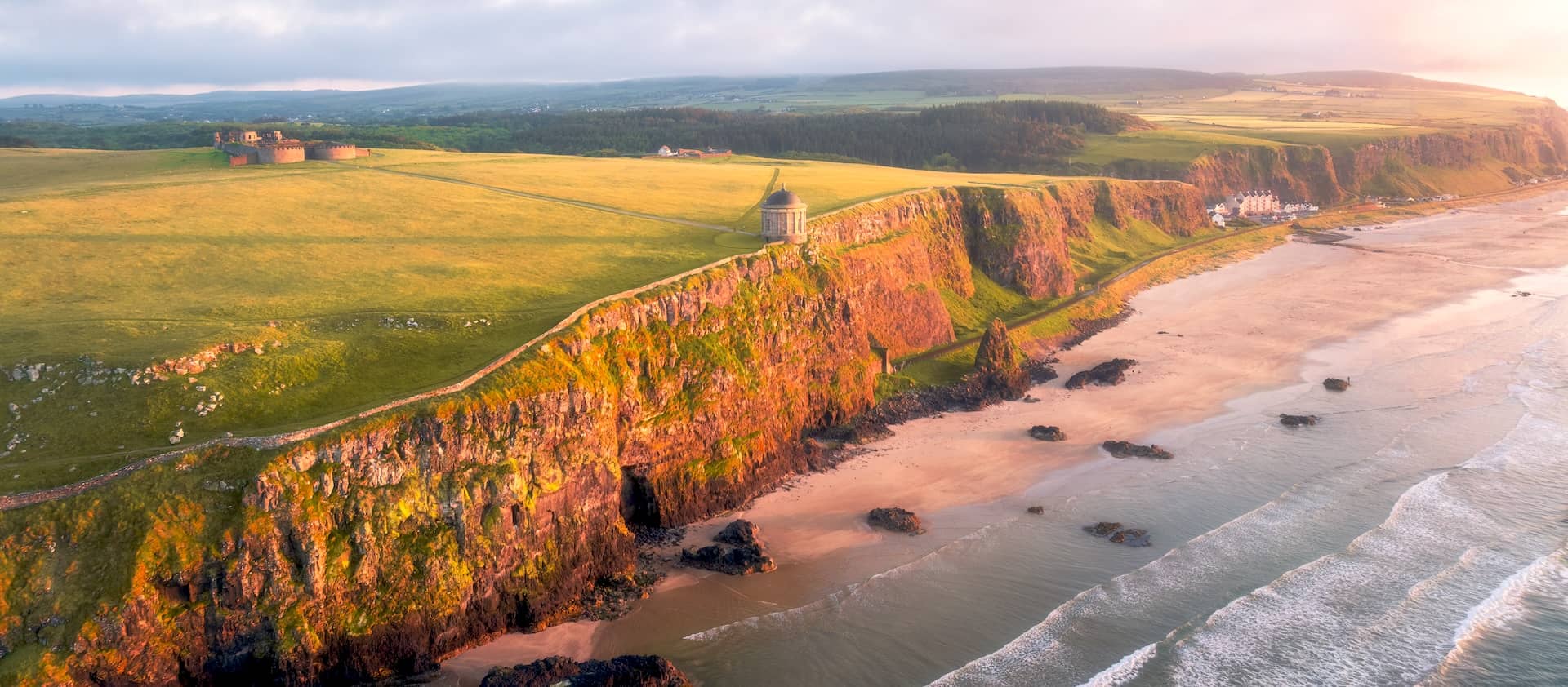 Panoramic sunset view of Mussenden Temple and Downhill Beach along the Causeway Coastal Route, County Londonderry.