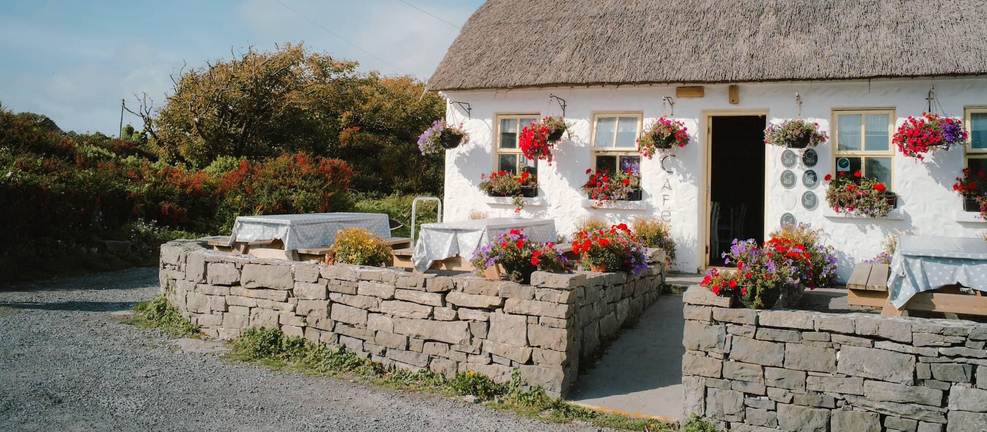 Coastal café cottage with a thatched roof and colourful flower baskets, on the Aran Islands, County Galway.