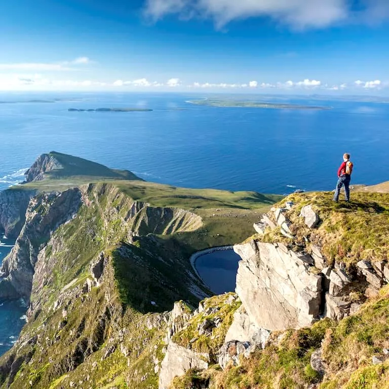 Hiker overlooking dramatic cliffs and Atlantic Ocean views on Achill Island, County Mayo.
