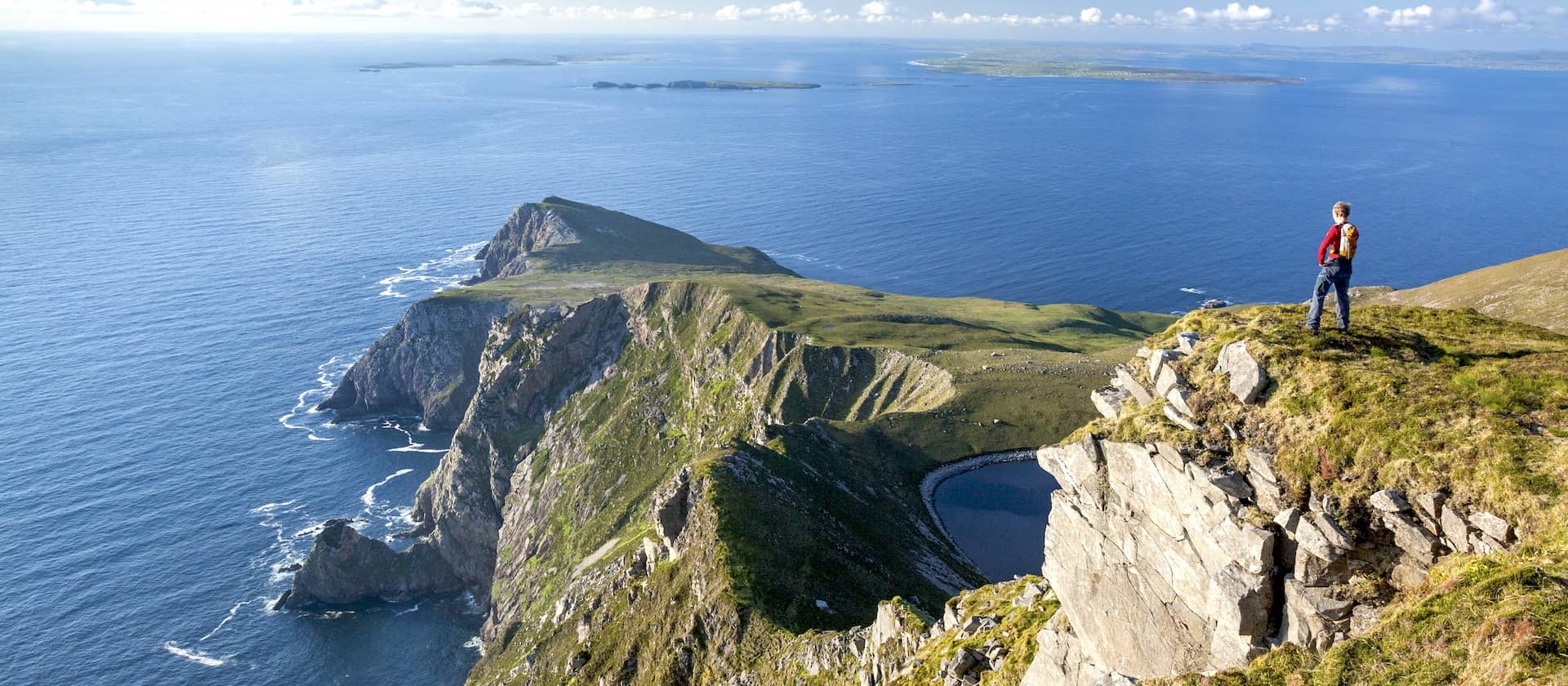 Hiker overlooking dramatic cliffs and Atlantic Ocean views on Achill Island, County Mayo.