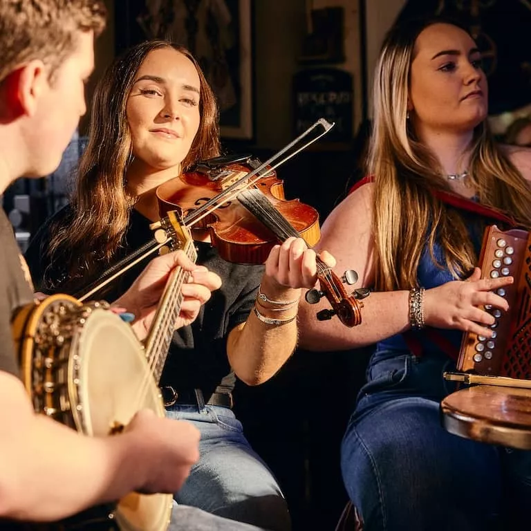 Traditional Irish music session at Kelly’s Cellars in Belfast with musicians playing fiddle, banjo and concertina.