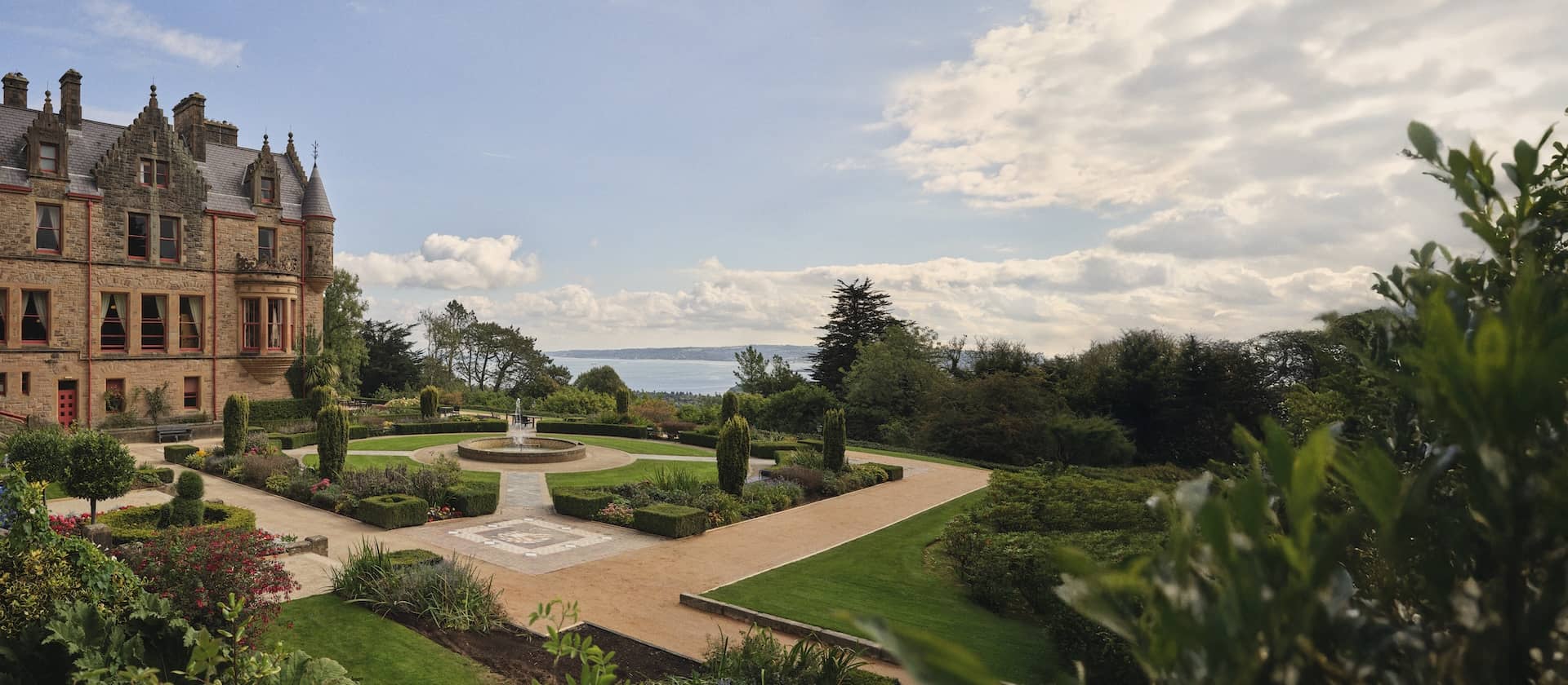 Belfast Castle and formal gardens with fountain overlooking Belfast Lough, County Antrim.