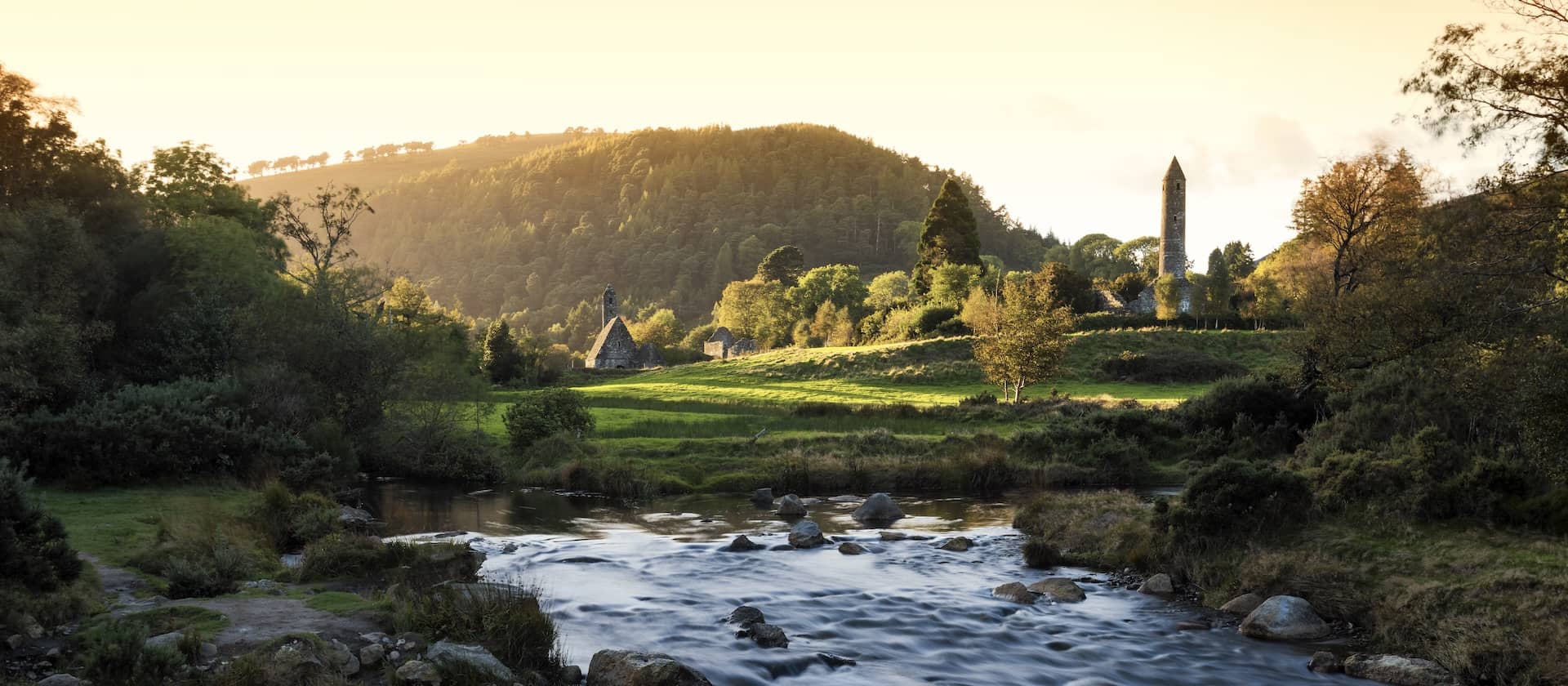Herfstkleuren rondom de monastieke ronde toren en het bovenste meer in Glendalough, county Wicklow, Ierland.