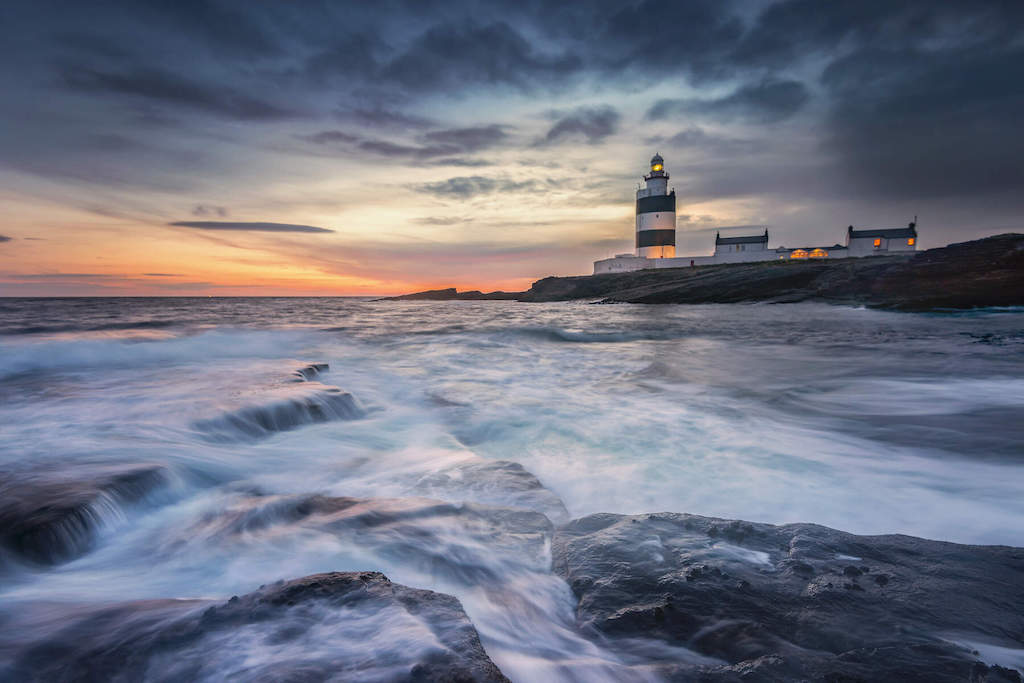 Hook Lighthouse on Hook Head, County Wexford, with waves breaking against the rocky shoreline.