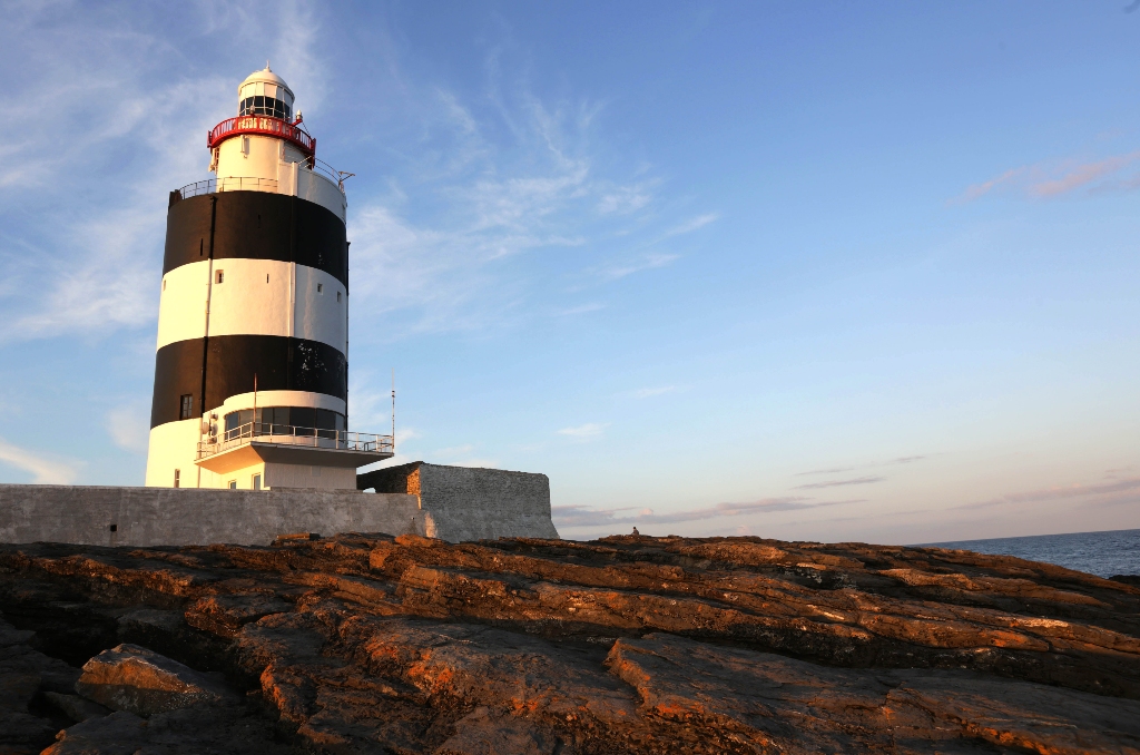 Hook Lighthouse, County Wexford, standing tall with black and white bands against a clear sky.