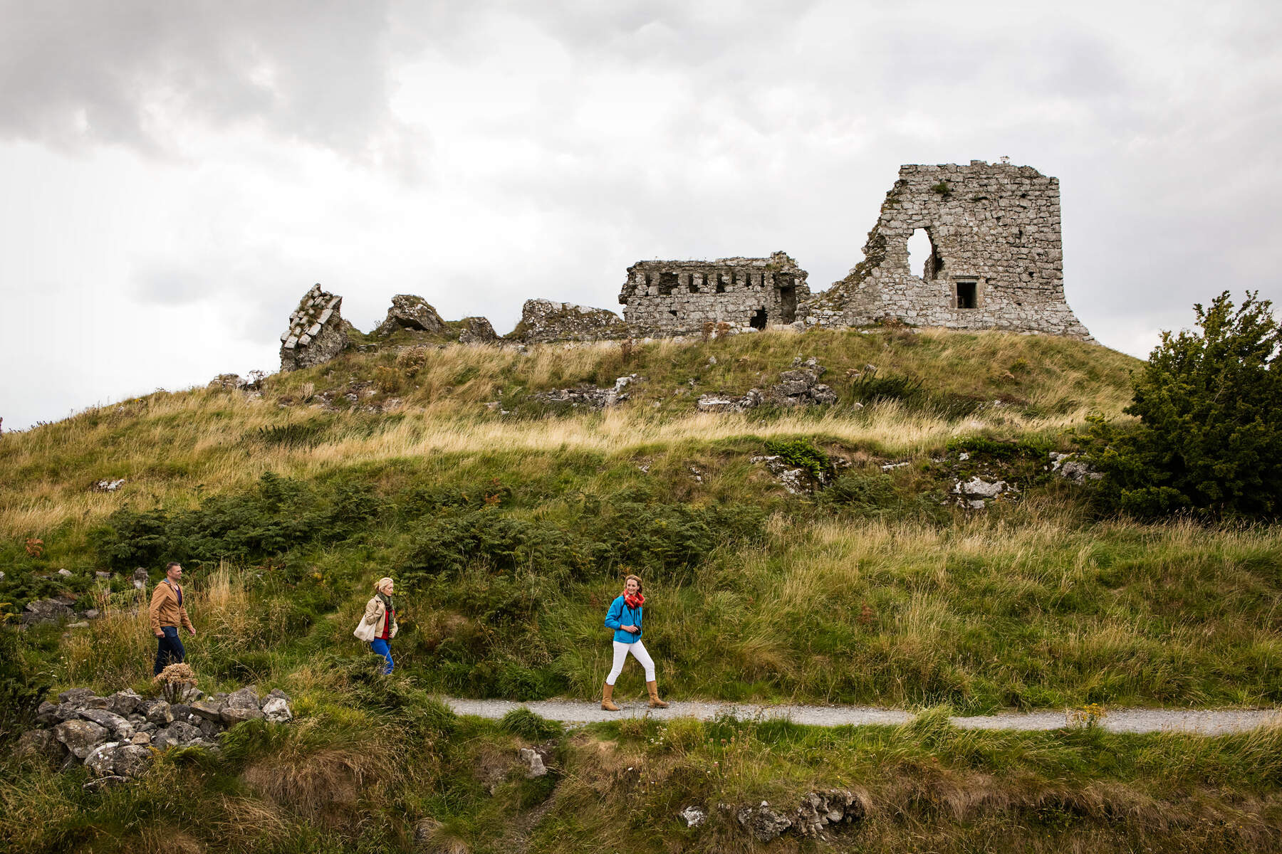 Visiteurs se promenant près des vestiges du Rocher de Dunamase dans le comté de Laois sur une colline herbeuse.