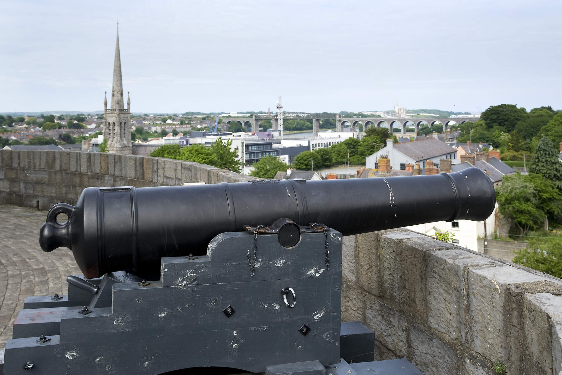 Historisch kanon op Millmount Fort in Drogheda, met uitzicht op het Boyne-viaduct en de kerktoren boven de daken.