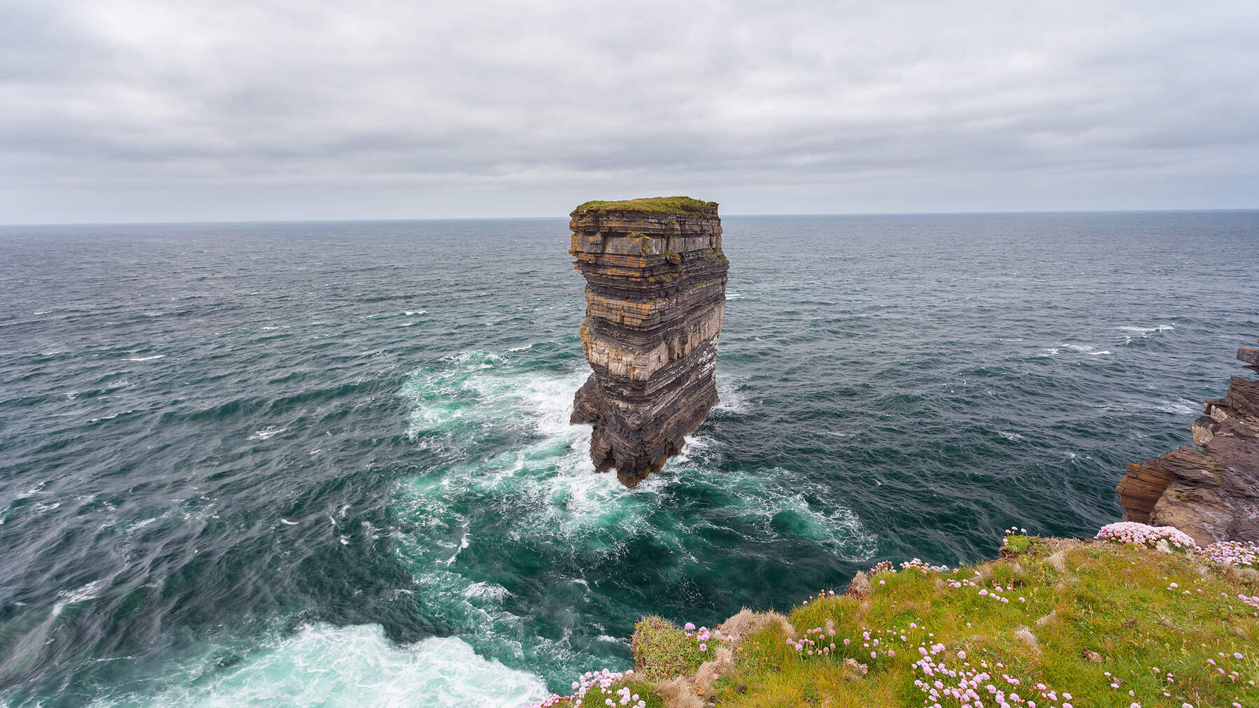 Une pile de mer spectaculaire s'élève de l'océan Atlantique à Downpatrick Head, comté Mayo, vue depuis la falaise herbeuse Berge.