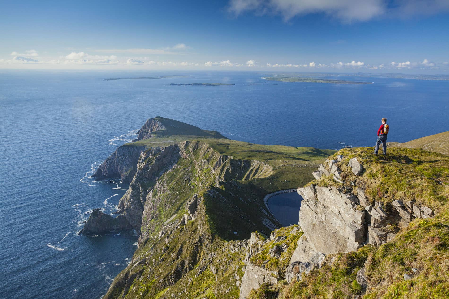 Hiker on Achill Island cliff with Atlantic views in County Mayo, Ireland.