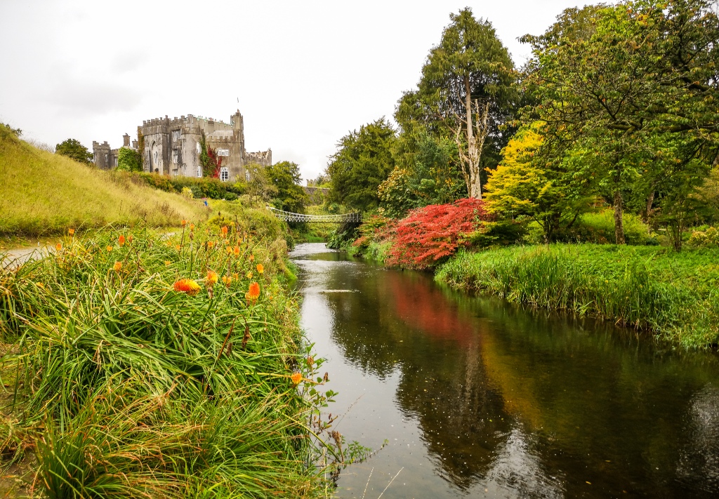 Le château de Birr dans le comté d'Offaly, vu au-delà d'une rivière calme bordée d'arbres et de couleurs automnales.