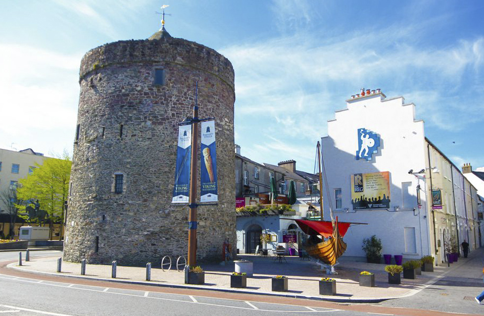 Medieval Reginald’s Tower in Waterford with Viking banners and a replica longship nearby.