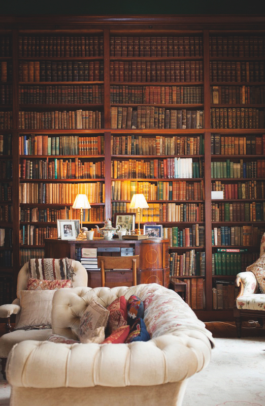 De weelderige bibliotheek in Clonalis House, county Roscommon, met boeken van muur tot muur, luxe zitplaatsen en tafellampen die een warme sfeer creëren.