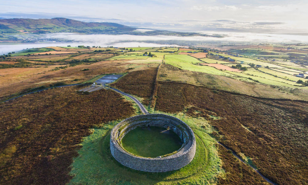Der Steinkreis Grianán von Aileach thront auf einem Hügel, umgeben von einem Flickenteppich aus Ackerland und nebligen Hügeln.
