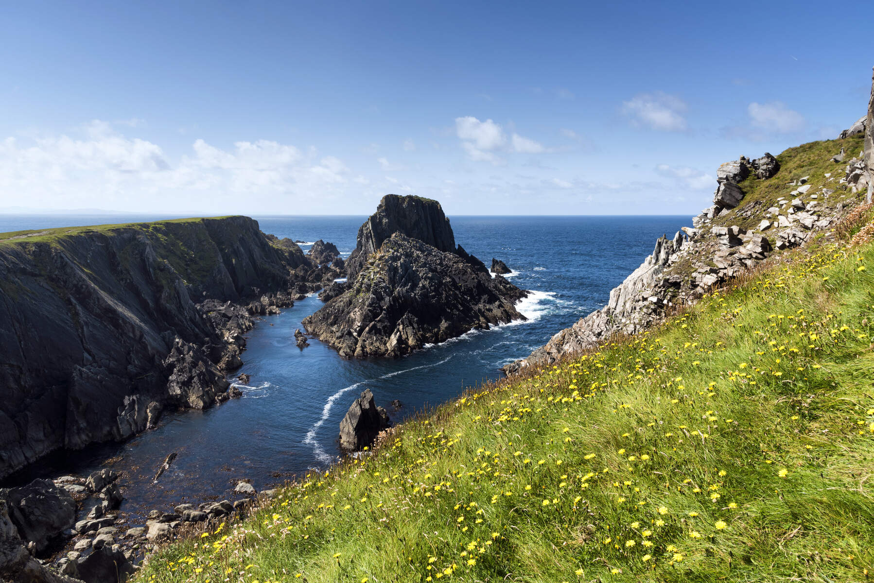 Felsige Klippen und felsige Seeberge ragen aus den klaren Gewässern des Atlantiks vor der Küste der Halbinsel Inishowen empor.