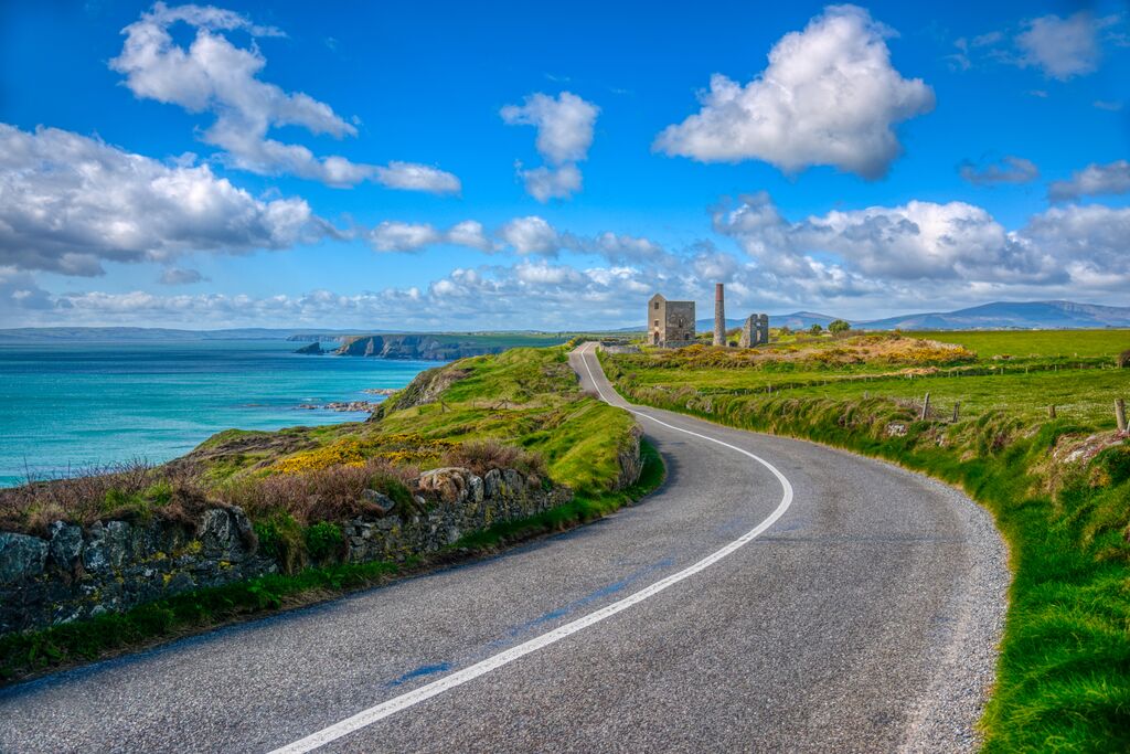Bochtige weg langs de Copper kust nabij Bunmahon, met ruïnes en kliffen boven de Atlantische Oceaan.