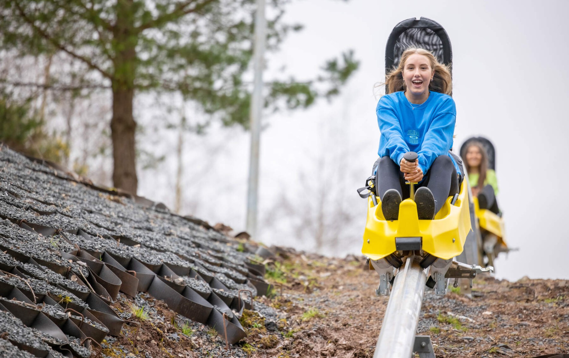 Young woman riding the zipline roller coaster at Colin Glen Forest Park, smiling.