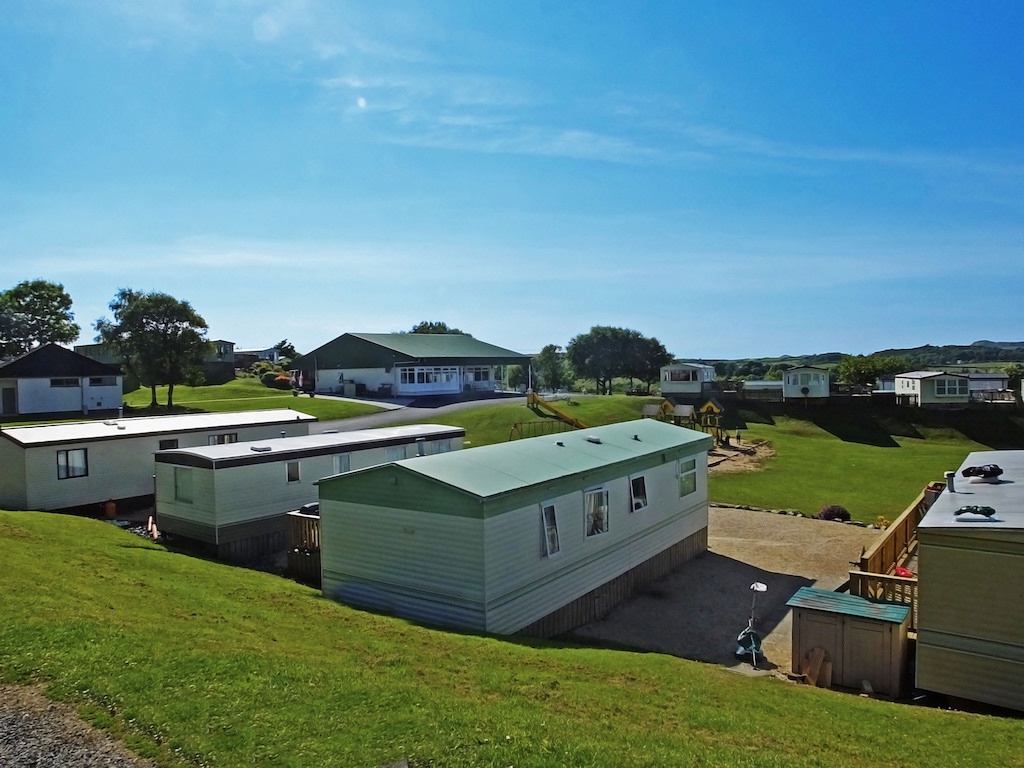 Static mobile homes at a family-friendly holiday park in Ireland, with a play area and clubhouse on a sunny day.