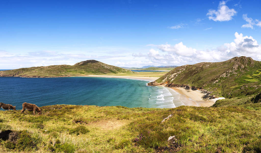 Trá Na Rossan Beach with golden sand, turquoise sea and rolling green hills in County Donegal.