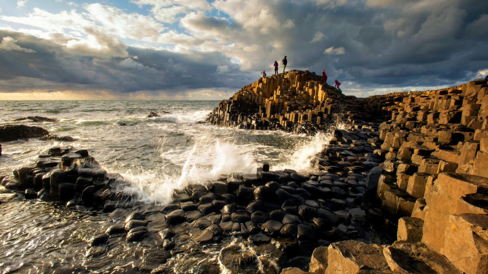 Le onde si infrangono contro le colonne di basalto della Giant's Causeway sulla costa della contea di Antrim al tramonto.