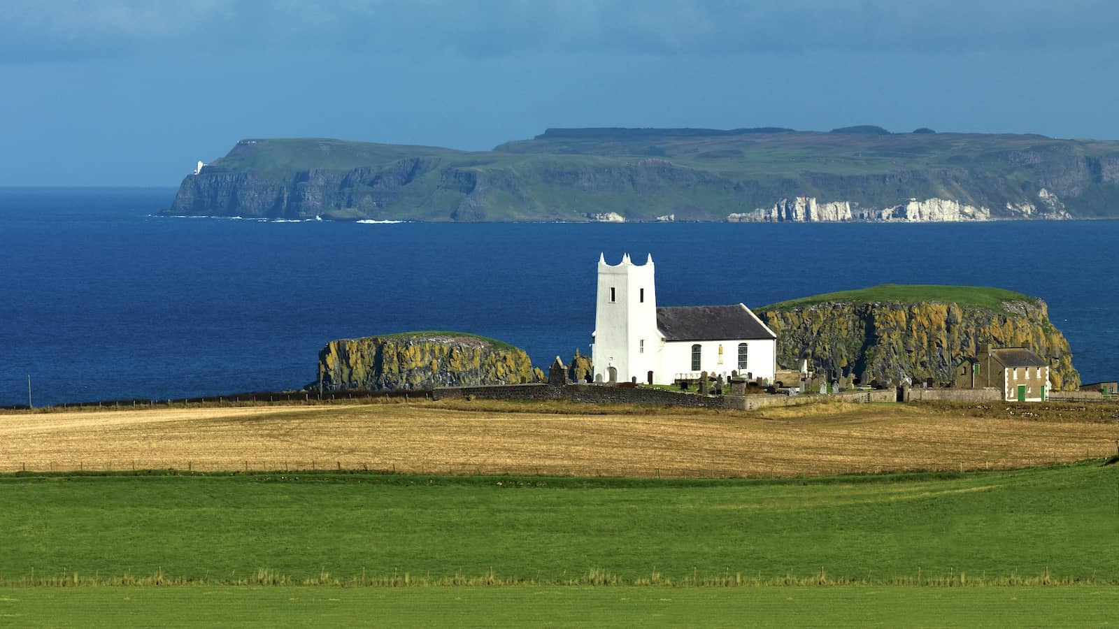 La chiesa di Ballintoy sulla costa della contea di Antrim, Irlanda del Nord, con vista sull'Oceano Atlantico e sull'isola di Rathlin.