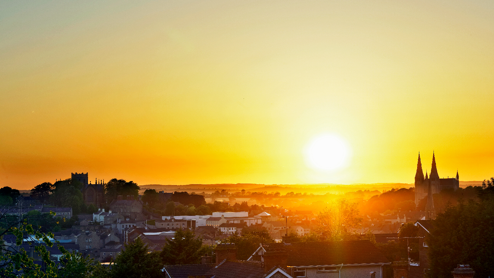 Sunset over Armagh city, with cathedral spires rising above rooftops and countryside.