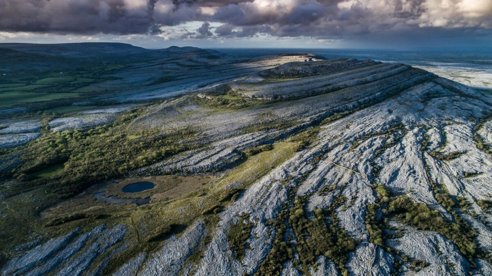 Aerial view of the Burren, County Clare, showing limestone pavements, rolling hills and the Atlantic coast.