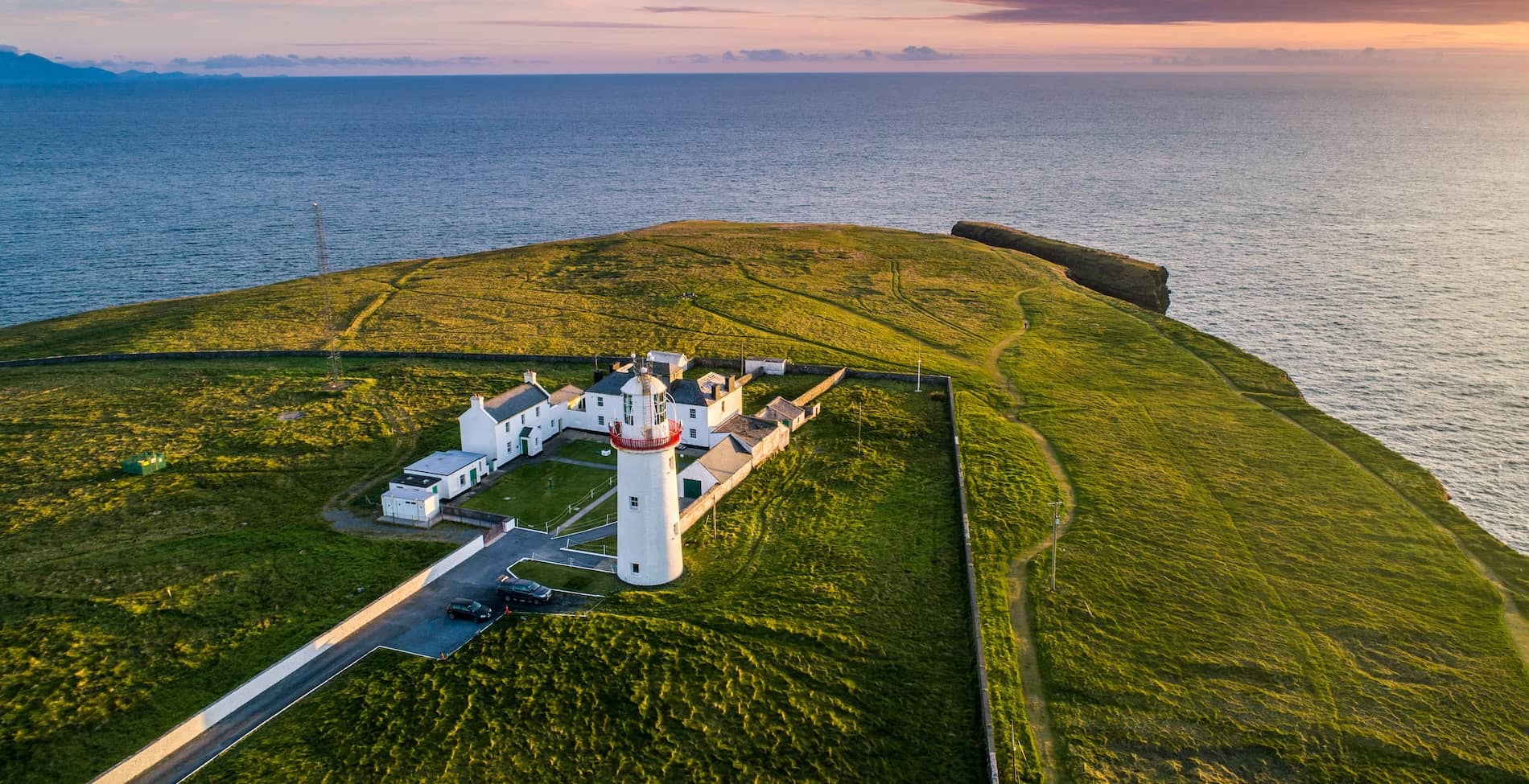 Loop Head Lighthouse overlooking dramatic Atlantic coastline at sunset, County Clare.
