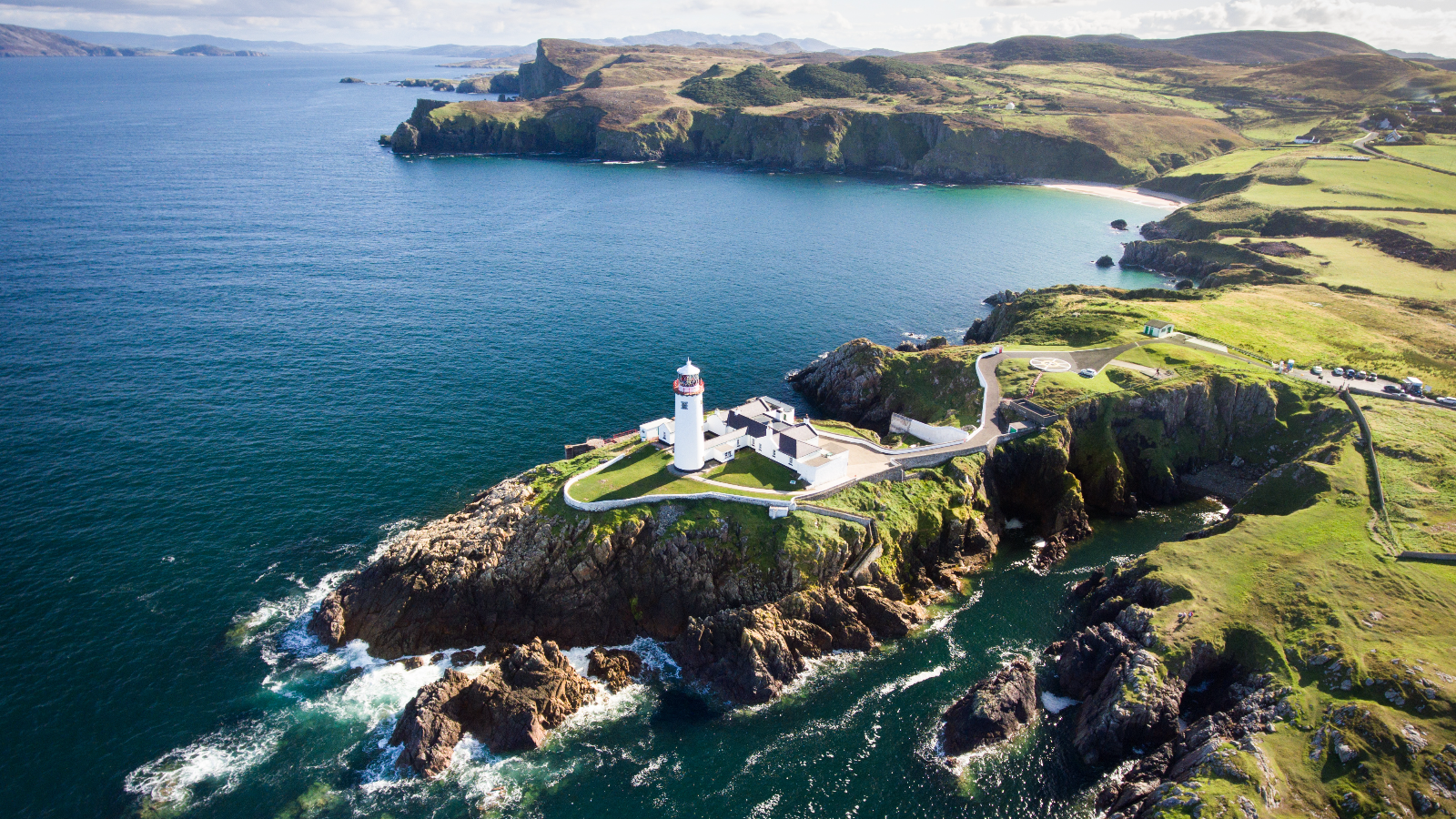 Fanad Head Lighthouse on rocky cliffs overlooking the Atlantic coast in County Donegal.