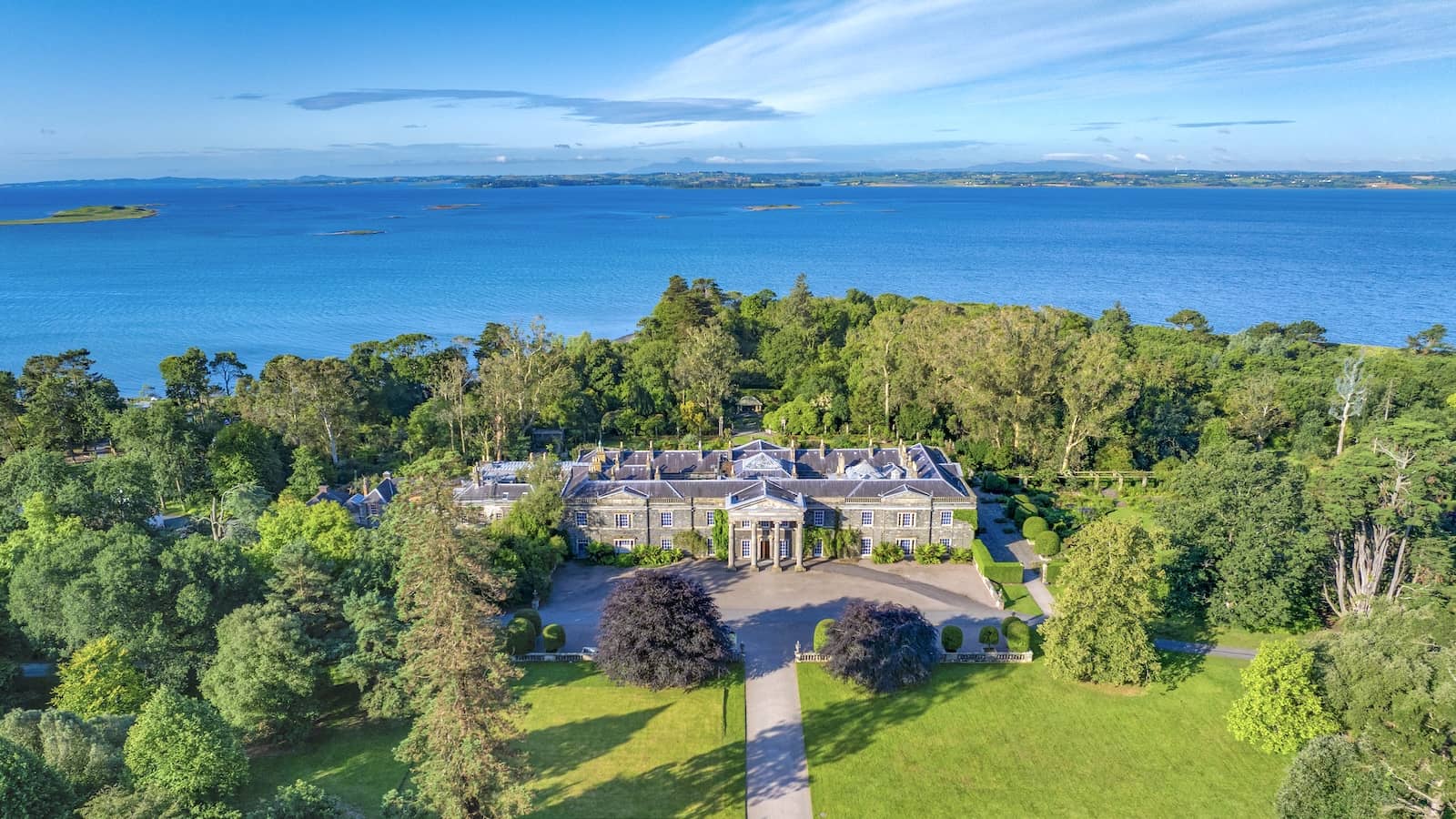 Luchtfoto van het landgoed Mount Stewart in County Down, omgeven door bossen en met uitzicht op Strangford Lough op een zonnige dag.