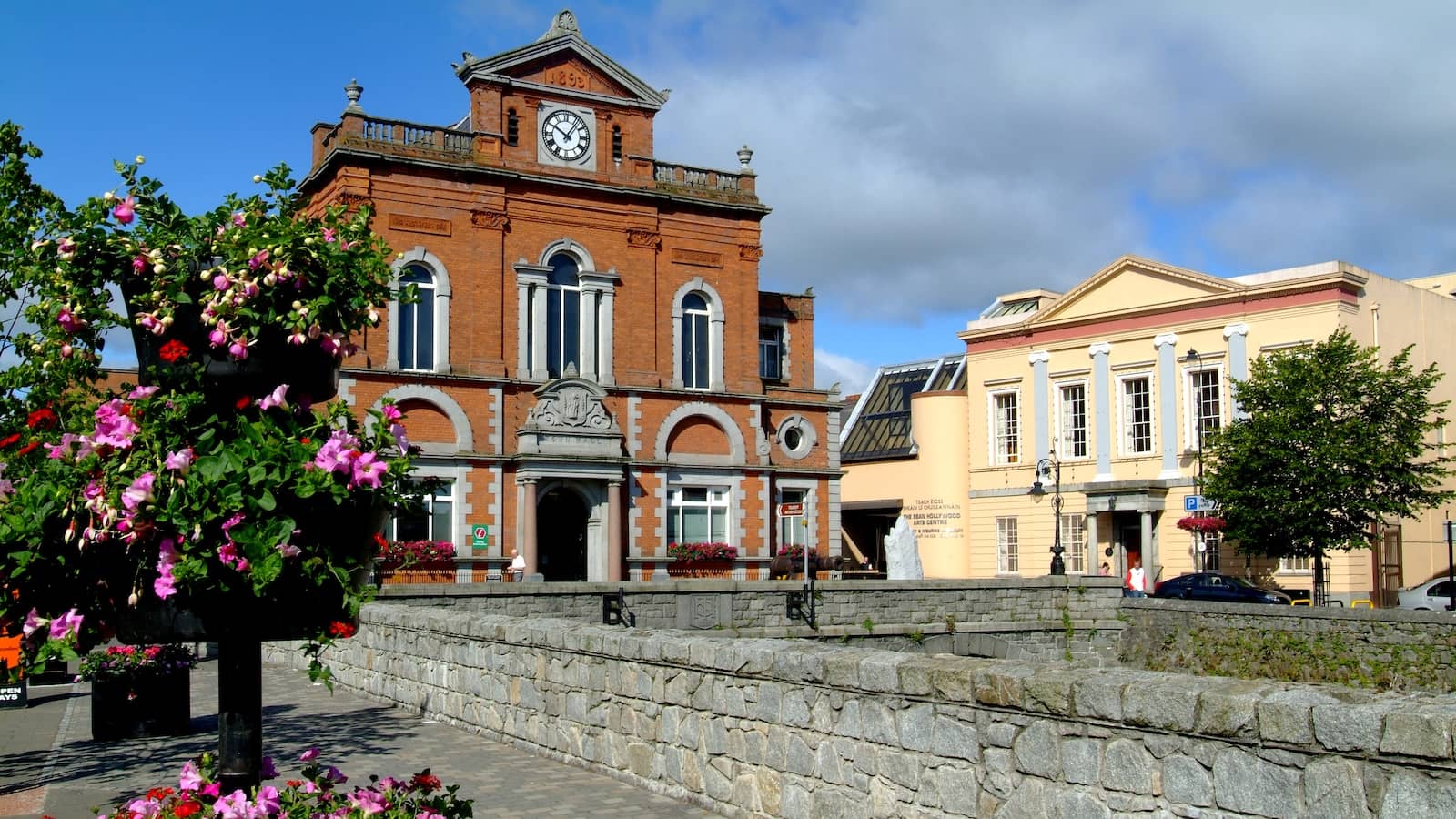 Historic Newry Town Hall beside the canal in County Down with colourful flower displays and blue skies overhead.