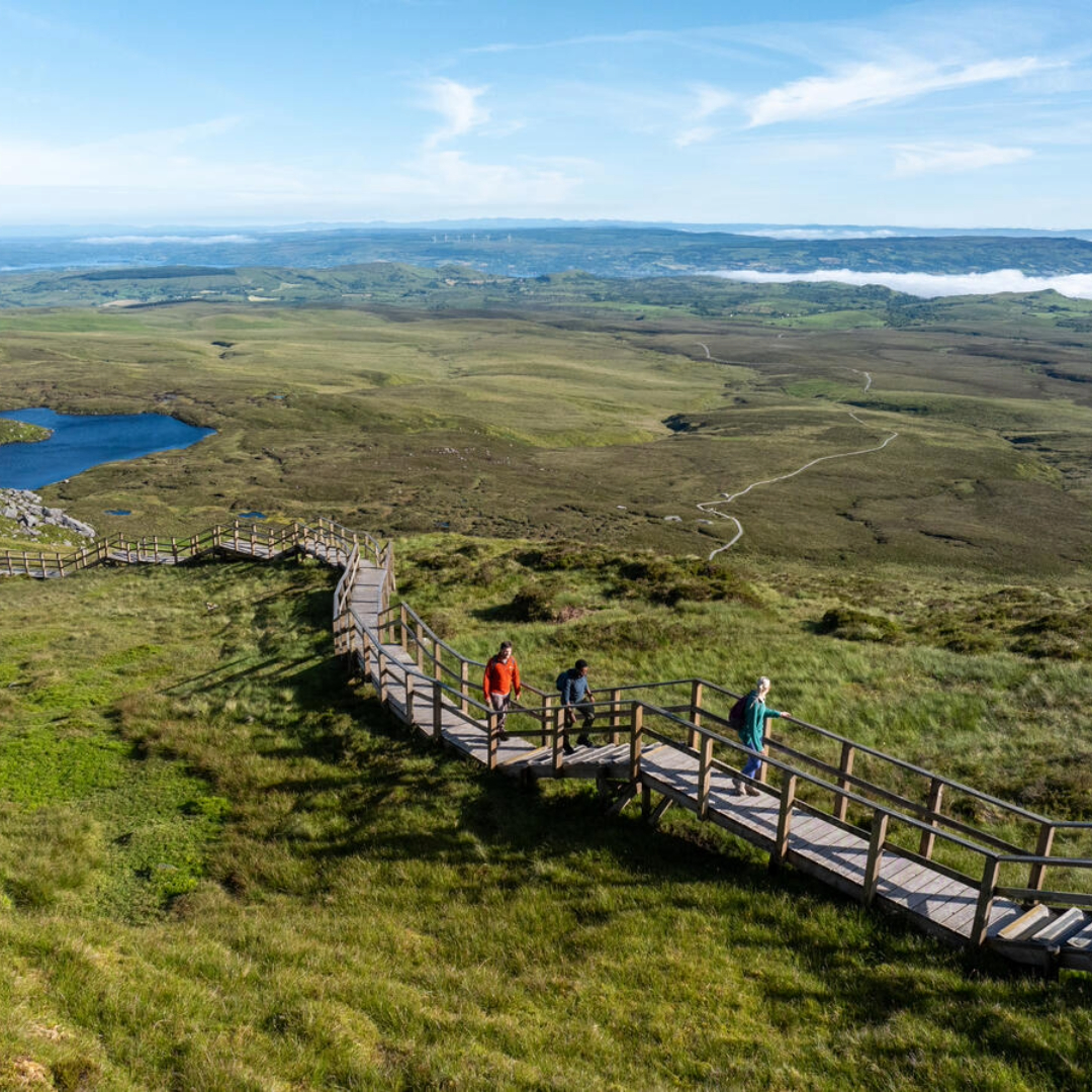 Visitors walk along the Cuilcagh Boardwalk overlooking blanket bog and lakes in County Fermanagh.
