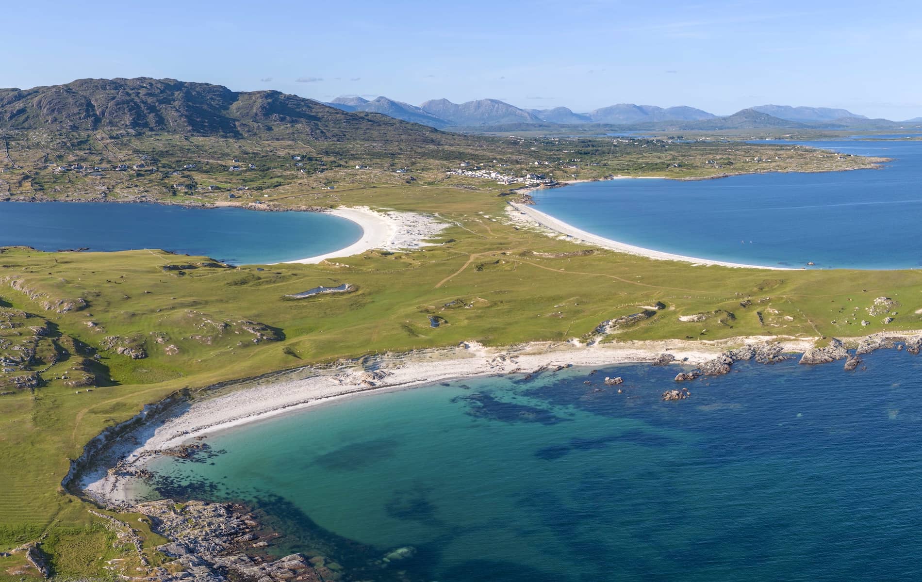 Aerial view of a curved white-sand beach and turquoise waters along the Connemara coast in Galway.
