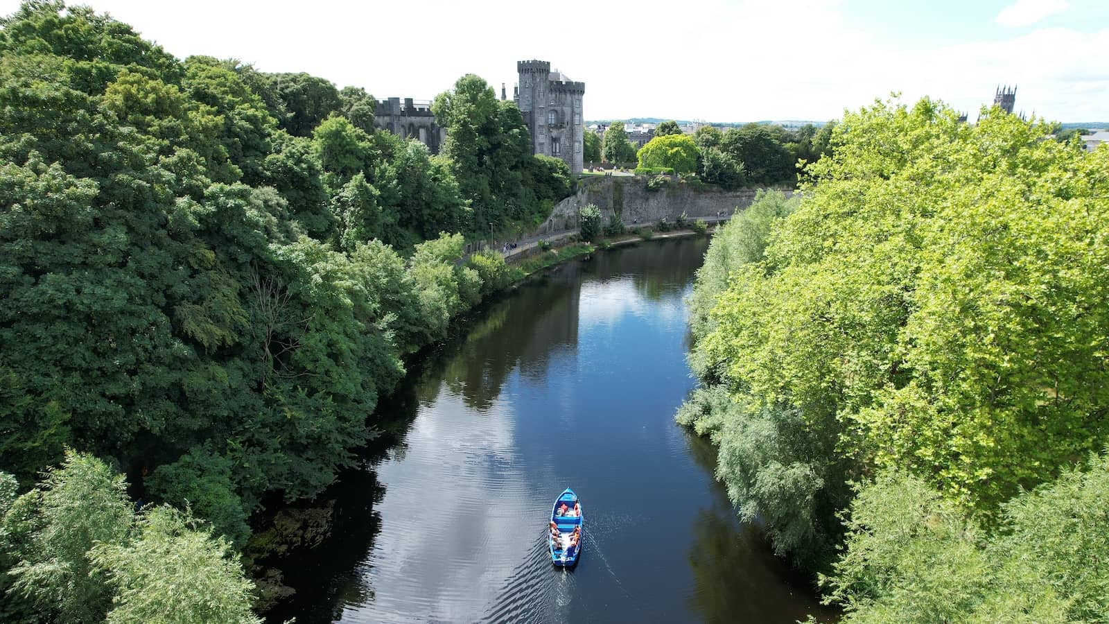 Excursion en bateau sur la rivière Nore avec vue sur le château de Kilkenny et ses berges verdoyantes.
