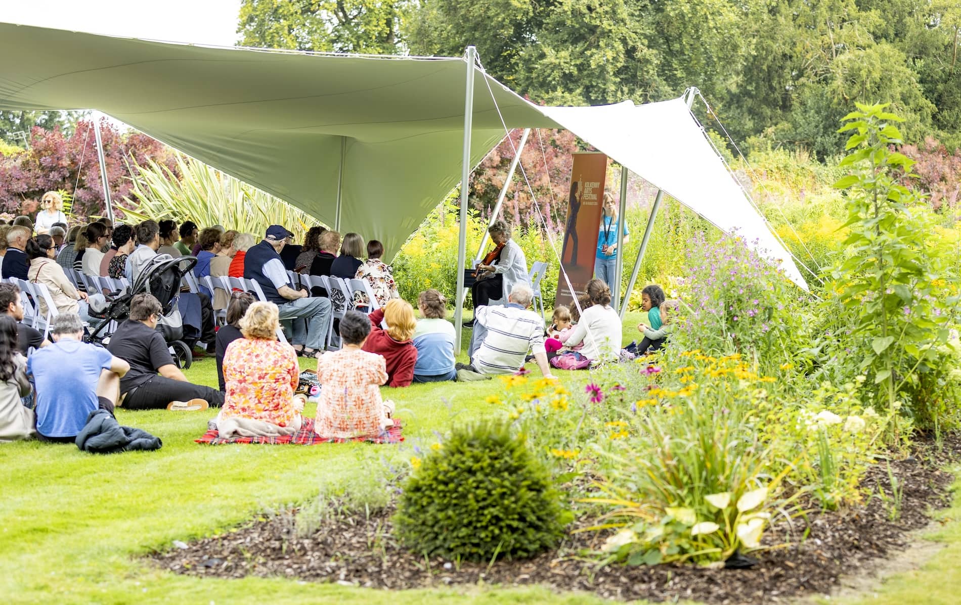 Pubblico che si gode la musica dal vivo al Kilkenny Arts Festival, in un giardino coperto.