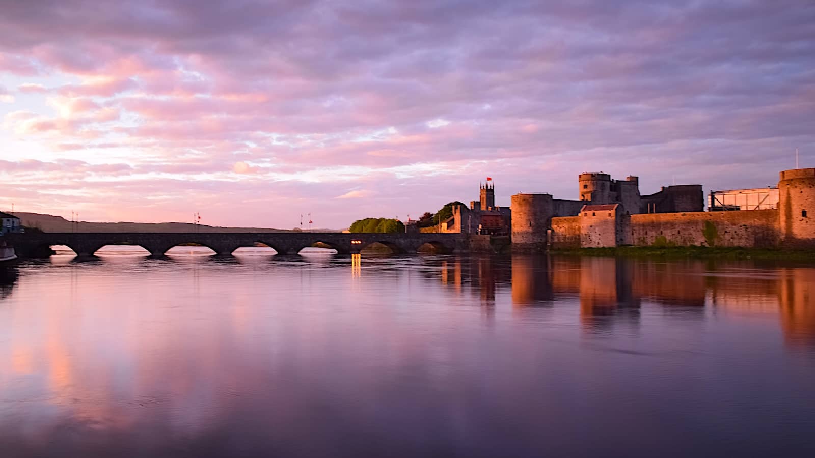 King John’s Castle and Thomond Bridge reflected in the River Shannon at dusk in Limerick city.