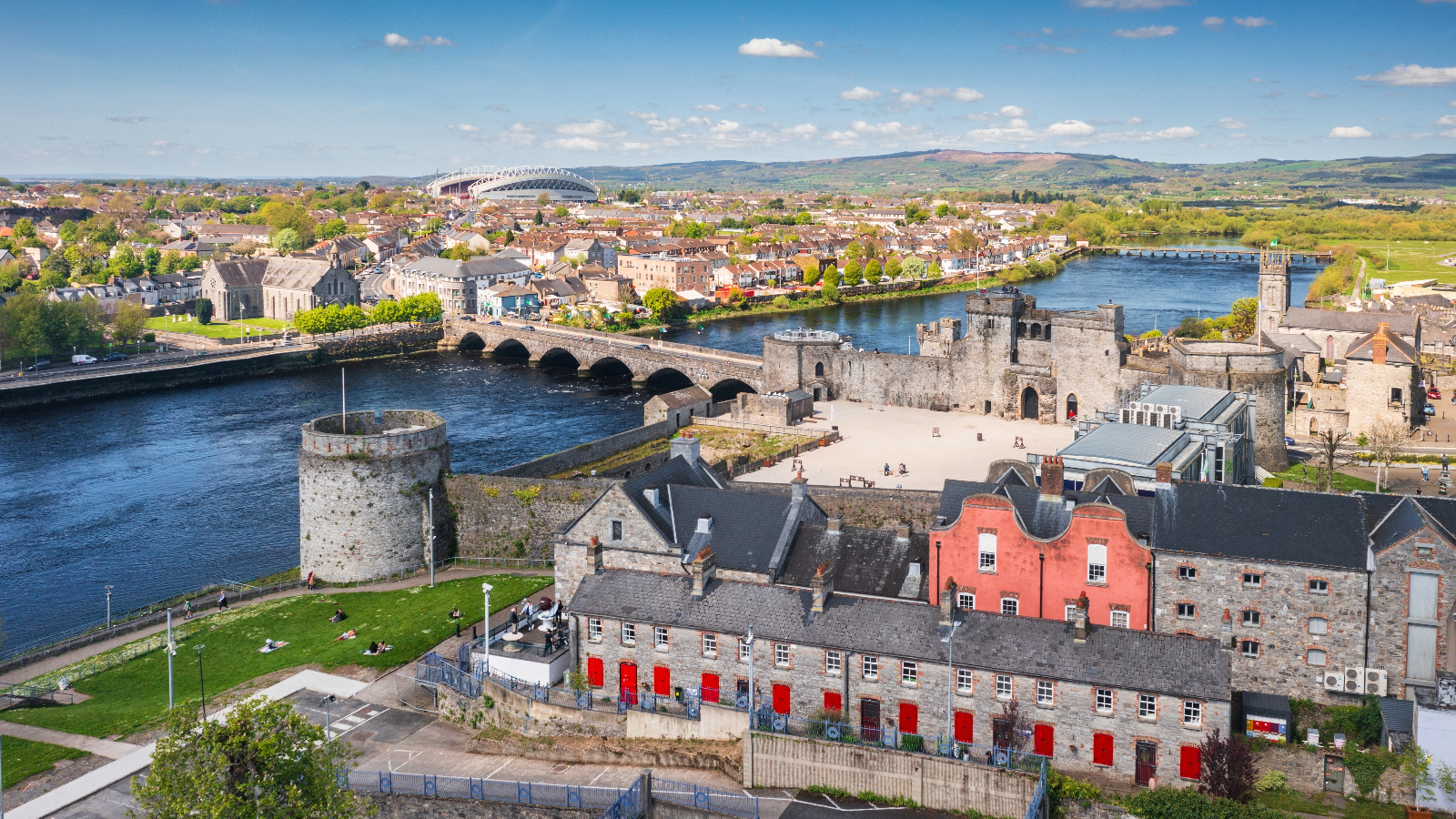 Aerial view of Limerick city with King John’s Castle, the River Shannon, and rows of colorful buildings.